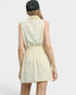 Woman wearing a light yellow sleeveless dress with a black cap on a white background
