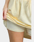 Close-up of a person wearing a light yellow dress with a plain background