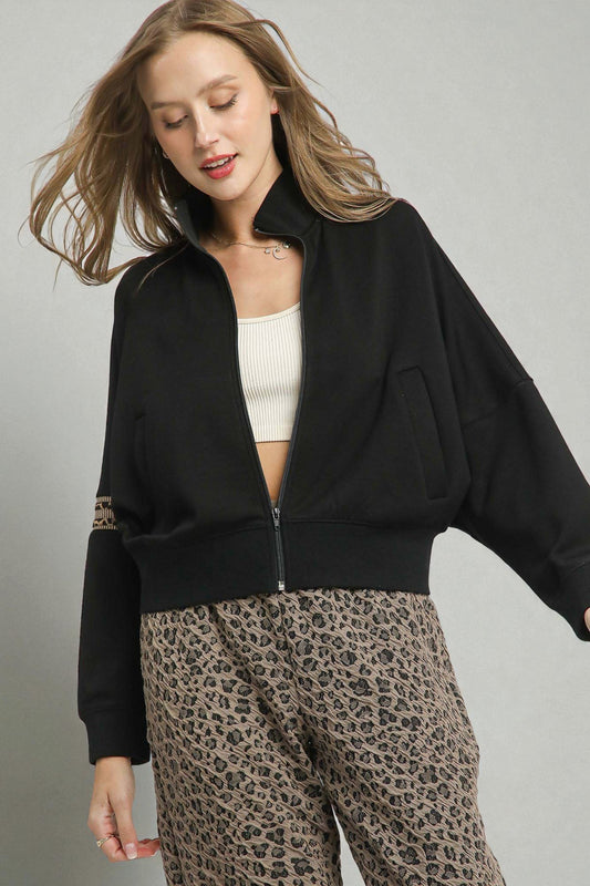 Woman wearing a black jacket and leopard print pants on a gray background