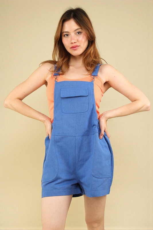 Woman wearing blue overalls against a beige background