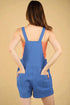 Person wearing a blue romper with an orange top against a beige background