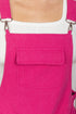 Close-up of a bright pink denim apron with a pocket and straps on a white background