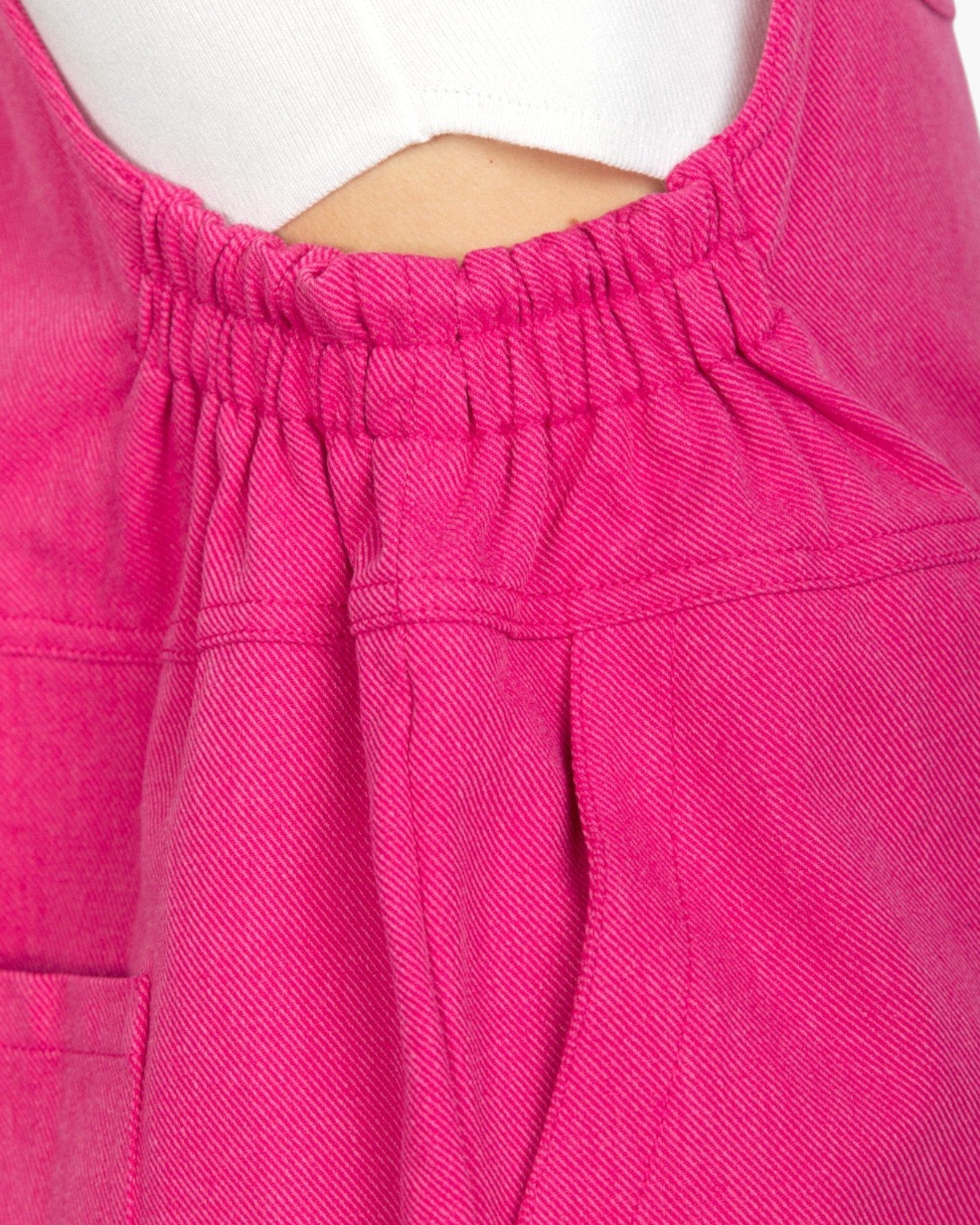 Close-up of a bright pink garment with an elasticized gathered neckline, shown on a mannequin or dress form against a white background.