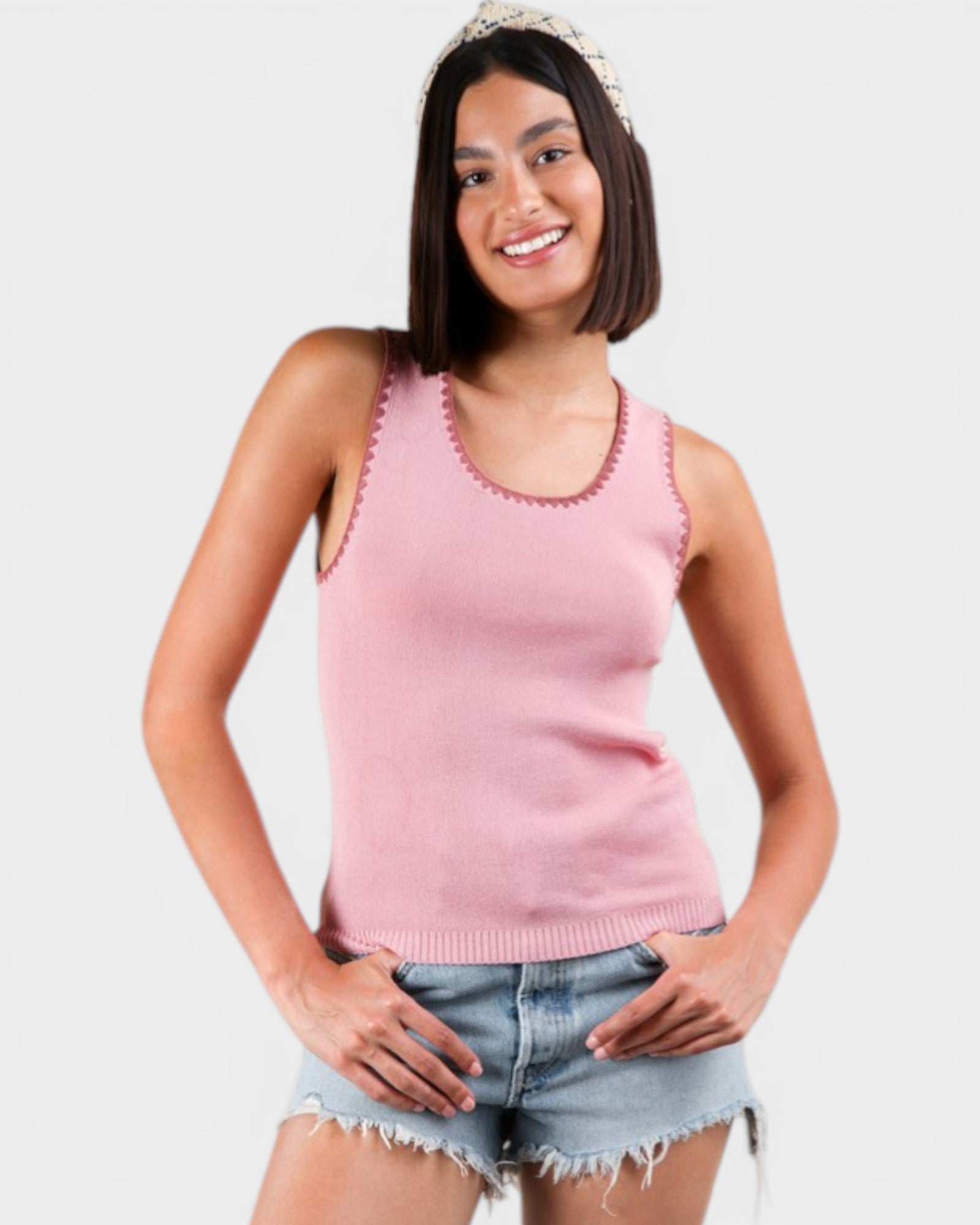 Woman wearing a pink sleeveless top with a white background