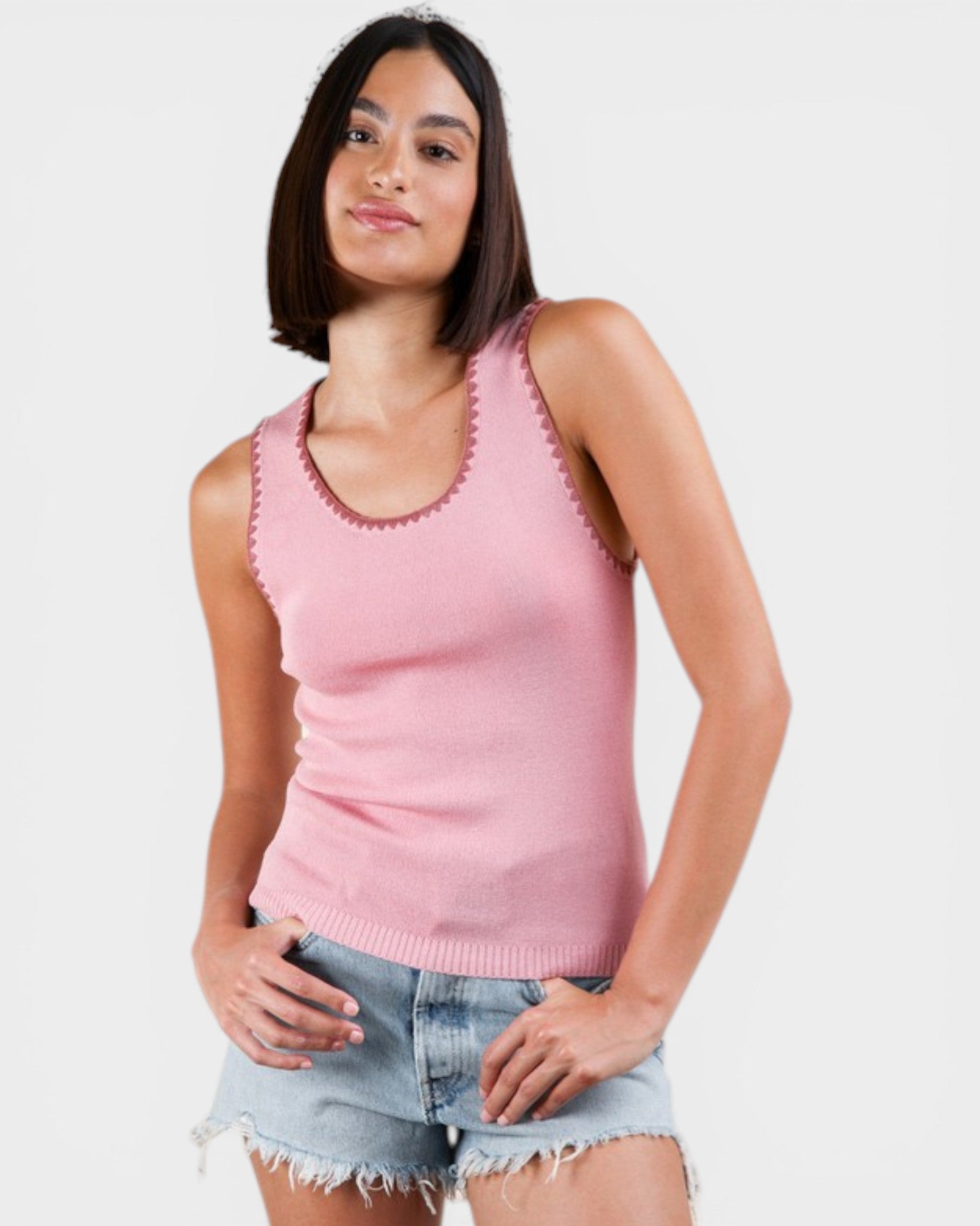 Woman wearing a pink sleeveless top with a white background