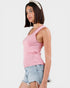 Woman wearing a pink knitted tank top and denim shorts on a white background