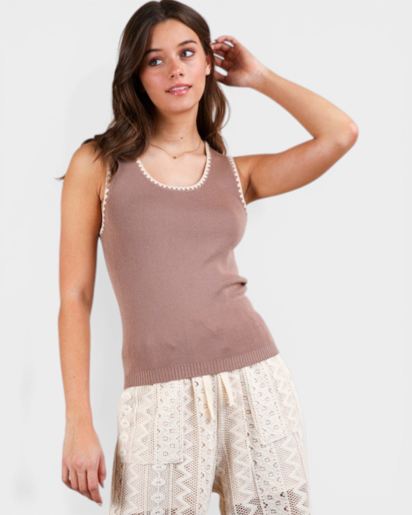 Woman wearing a brown sleeveless top with lace trim on a white background