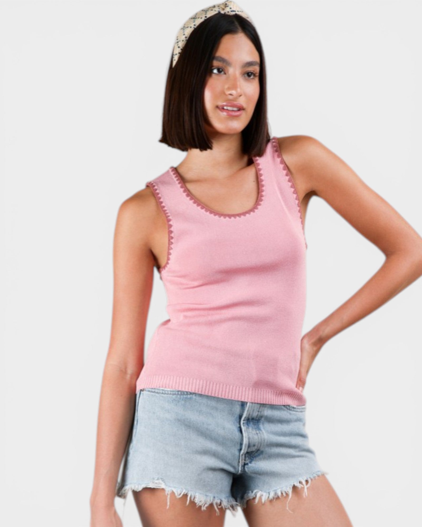 Woman wearing a pink tank top and denim shorts on a white background
