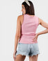 Woman wearing a pink sleeveless top and denim shorts on a white background