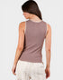 Woman wearing a sleeveless brown top with lace trim on a white background