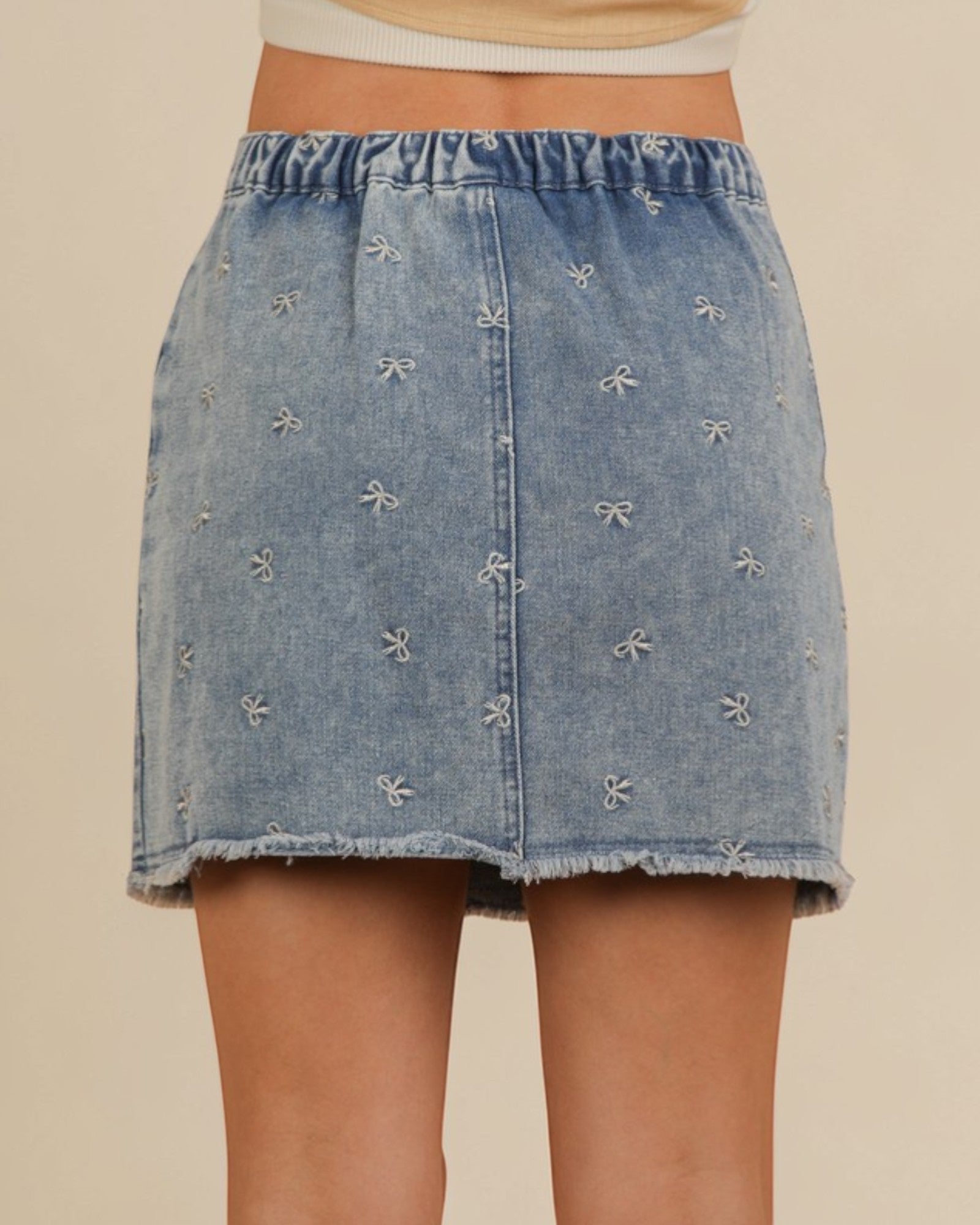 Denim skirt with bow details on a beige background