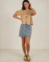 Woman wearing a beige top and denim skirt on a white background