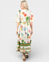 Woman wearing a colorful dress with floral and pineapple patterns on a white background