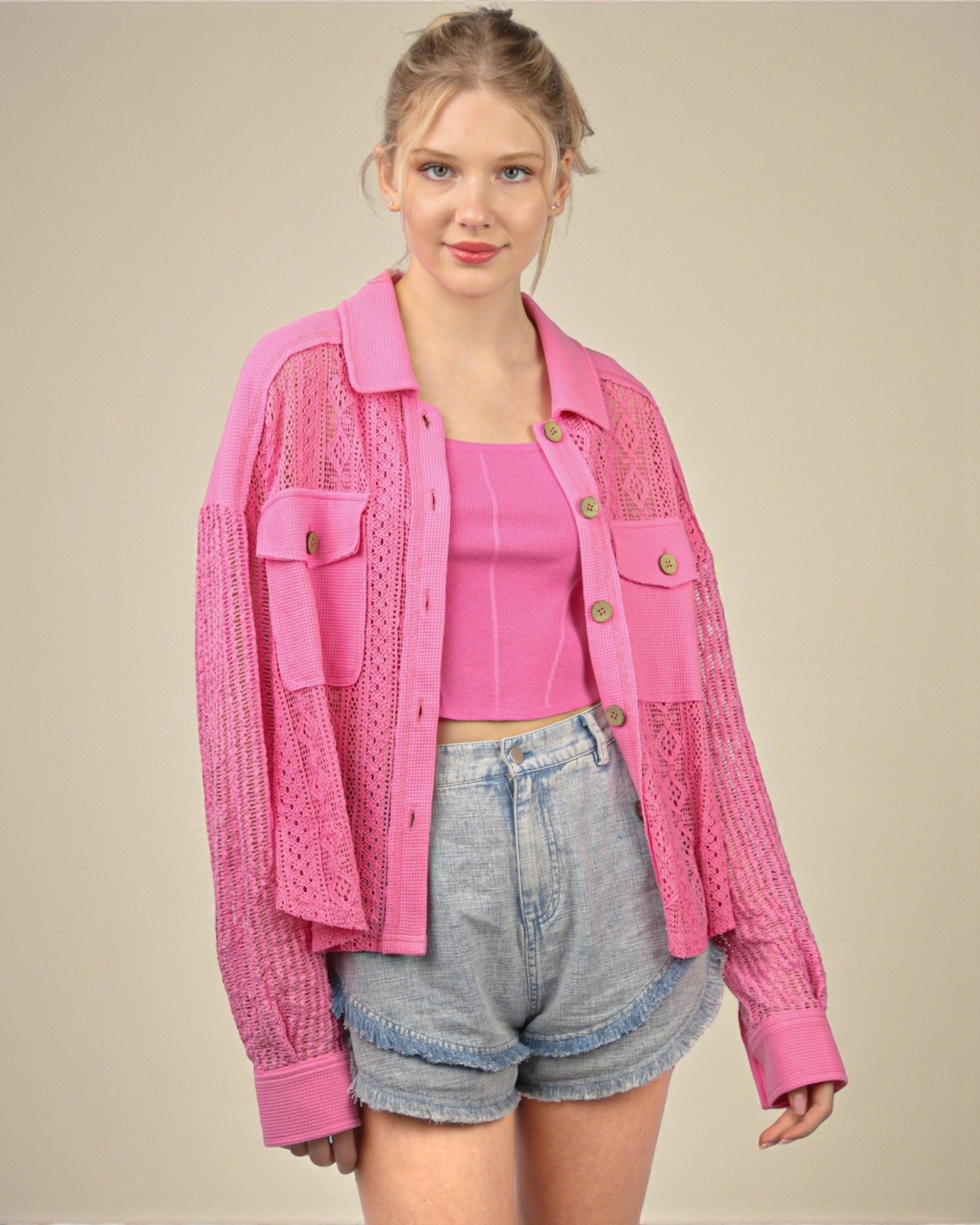Woman wearing a pink jacket and shorts on a beige background