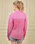 Woman wearing a pink shirt with lace detailing on a beige wall background