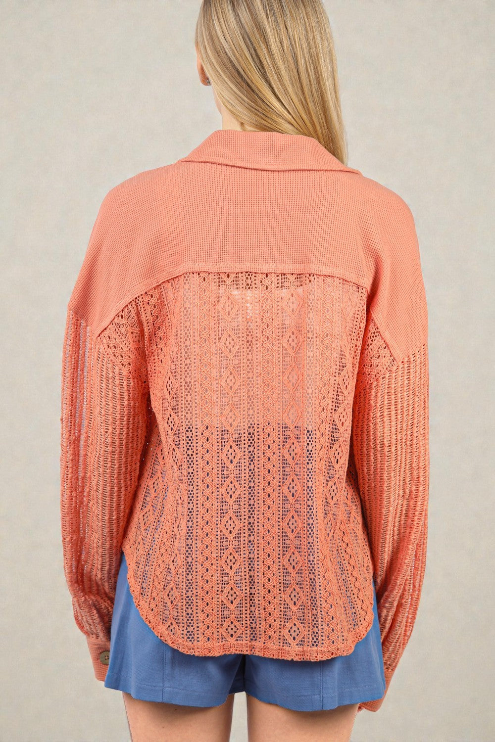 Person wearing a coral lace-up top with a beige background