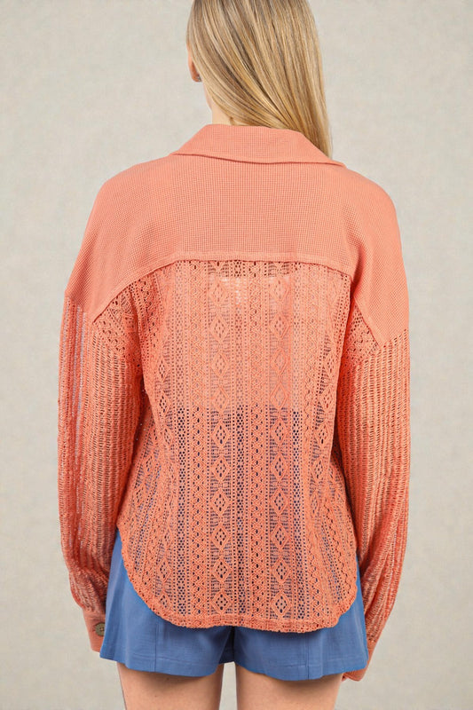 Person wearing a coral lace-up top with a beige background