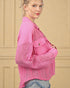 Woman wearing a pink jacket with a textured pattern against a beige background