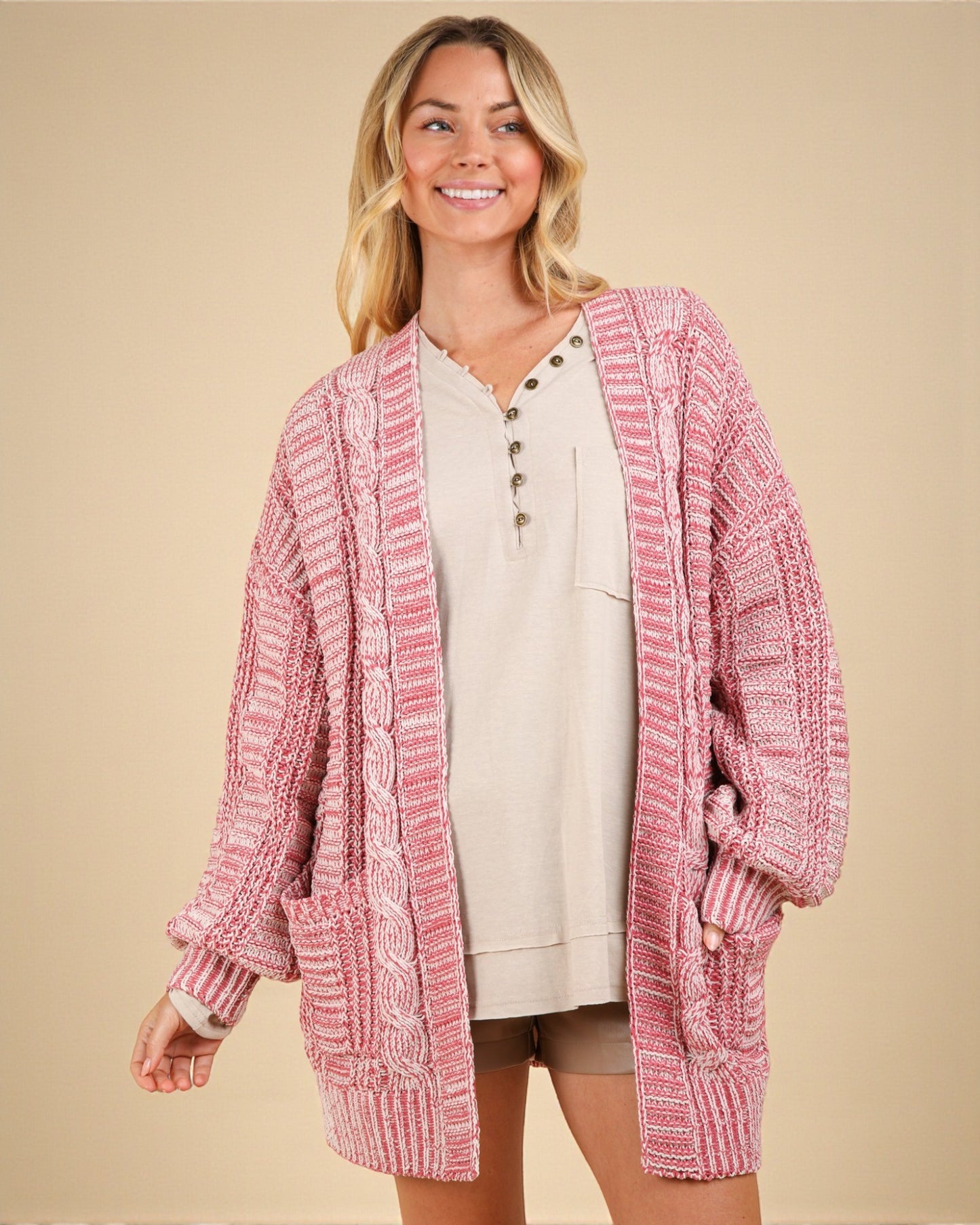 Woman wearing a pink knitted cardigan on a beige background