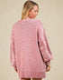 Woman wearing a pink textured cardigan against a beige background