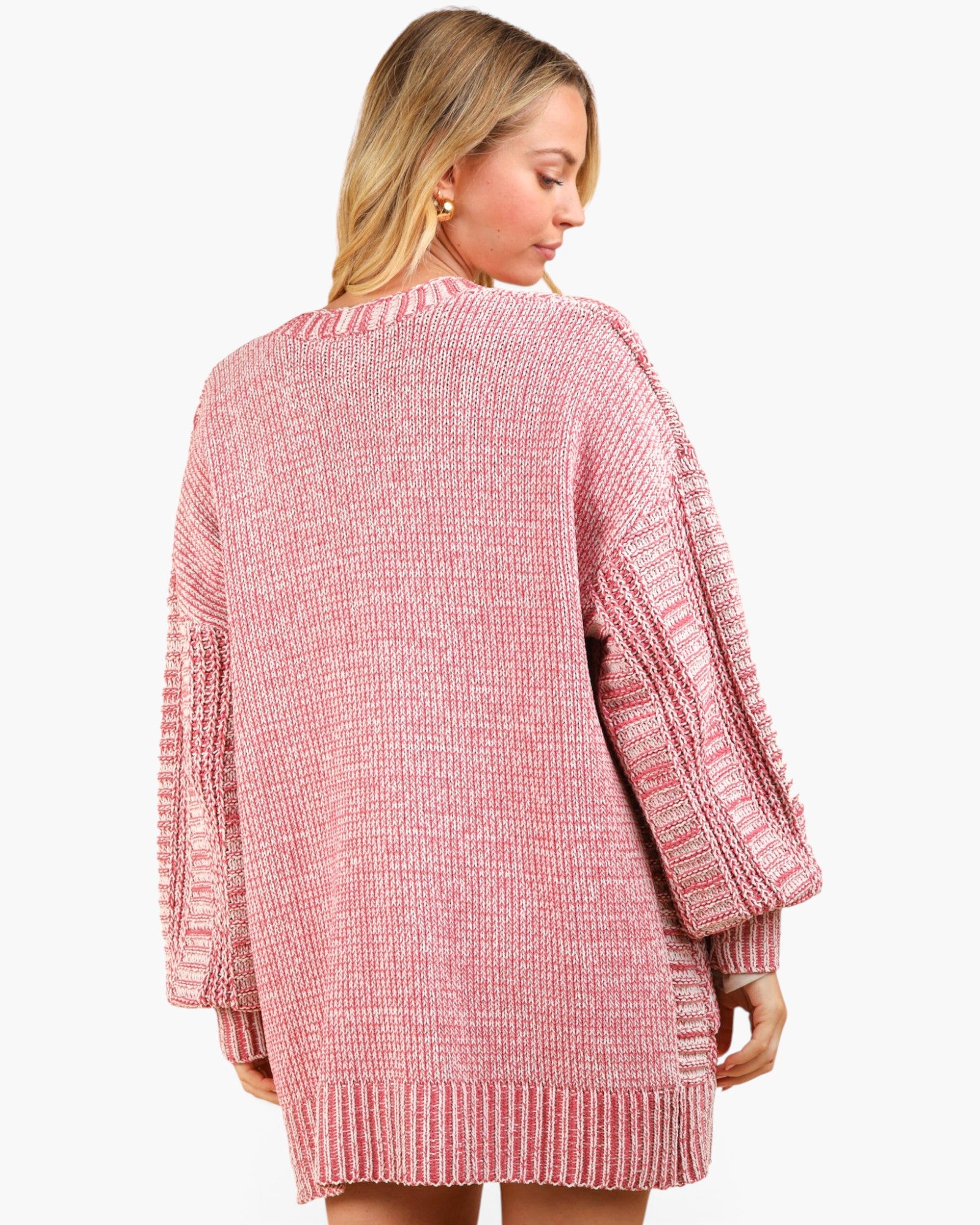A woman wearing an oversized pink marled knit sweater with textured sleeves, shown from the back against a plain light background.