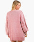 A woman wearing an oversized pink marled knit sweater with textured sleeves, shown from the back against a plain light background.