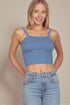 Woman wearing a blue ribbed crop top and jeans against a beige background
