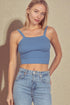 Woman wearing a blue ribbed crop top and jeans against a beige background