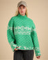 Person wearing a green sweater with white patterns on a beige background