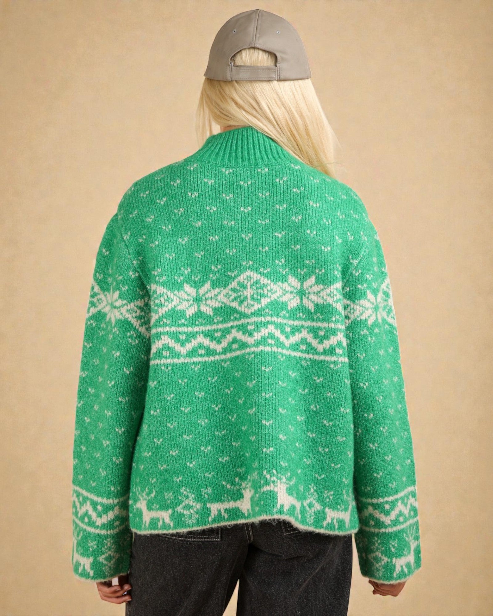 Person wearing a green sweater with white patterns on a beige background