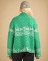 Person wearing a green sweater with white patterns on a beige background