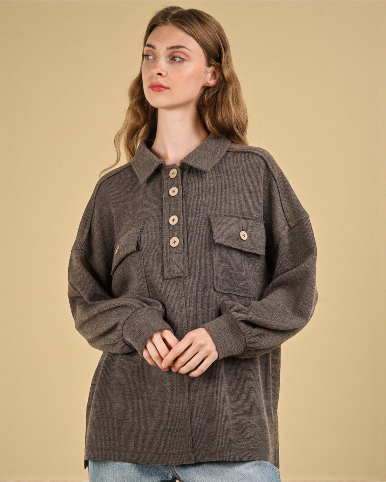 Woman wearing a brown jacket with button details on a beige background