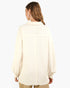 A woman shown from the back wearing a cream-colored, long-sleeved button-up shirt with a relaxed fit and a small collar, paired with beige pants against a plain white background.