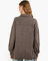 A woman viewed from the back wearing an oversized brown knit button-up shirt jacket with a collar and long sleeves, paired with light blue jeans against a plain white background.