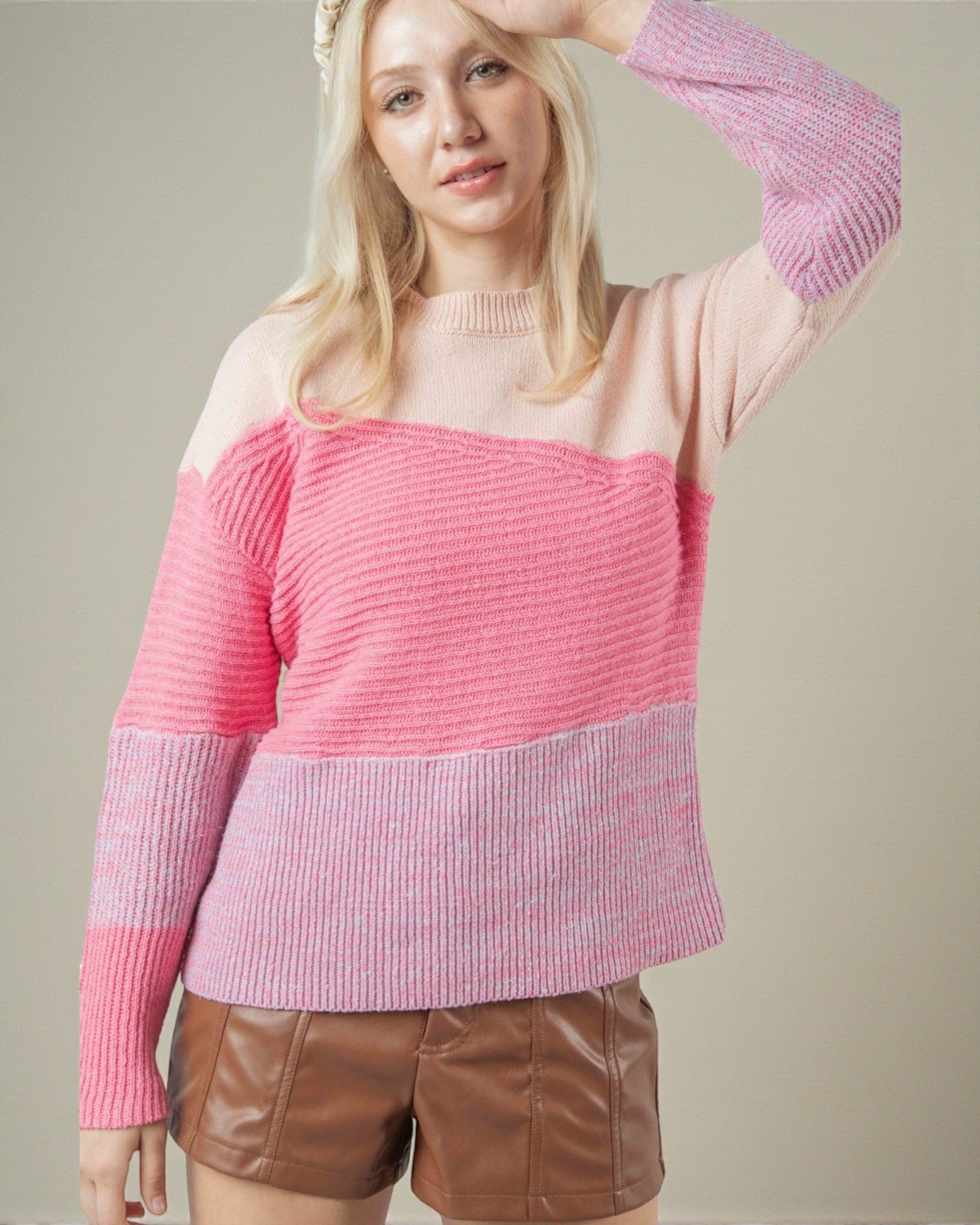 Woman wearing a pink sweater with a plain background