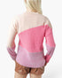A woman shown from the back wearing a color-block knit sweater with a light beige upper section, a bright pink middle section, and a pinkish-purple lower section, paired with brown shorts against a plain white background.
