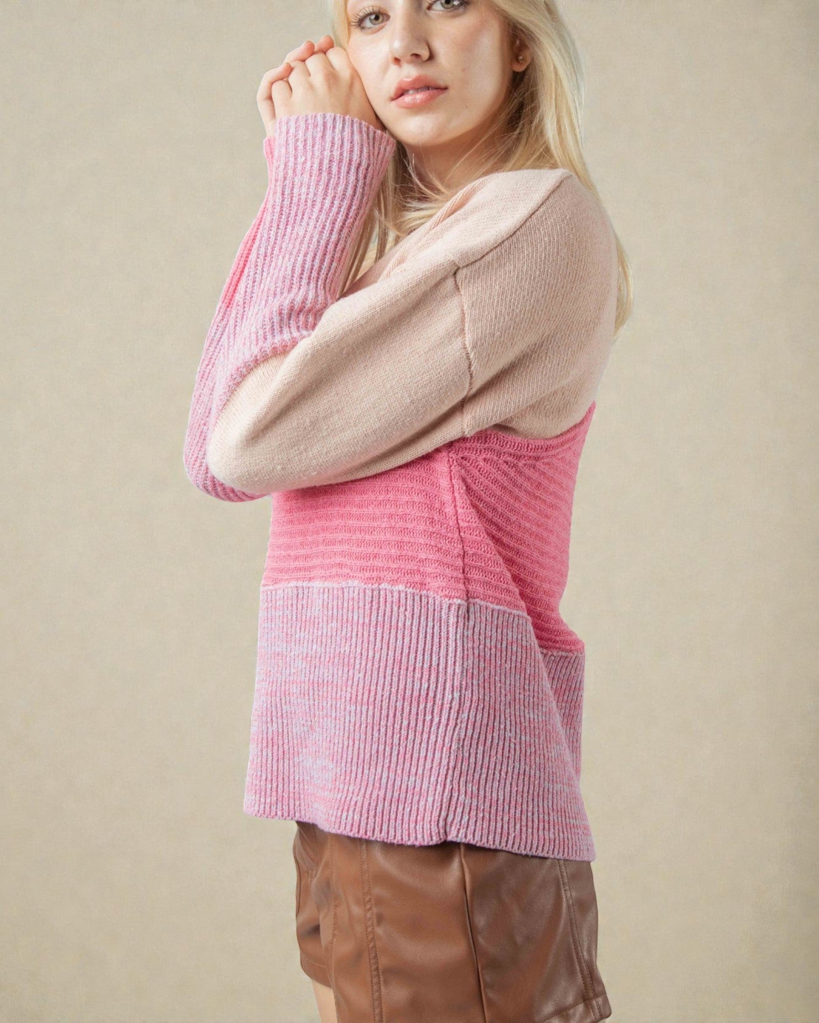 Woman wearing a pink and beige sweater against a beige background