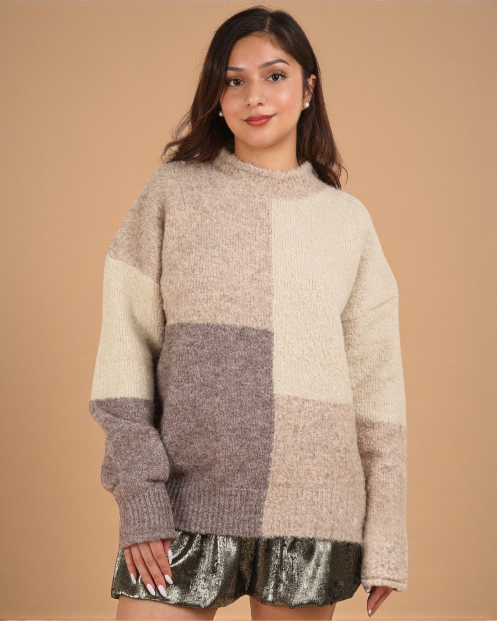 Woman wearing a patchwork sweater against a beige background