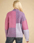 Person wearing a colorful patchwork sweater against a beige background