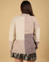 Person wearing a patchwork sweater with a plain background