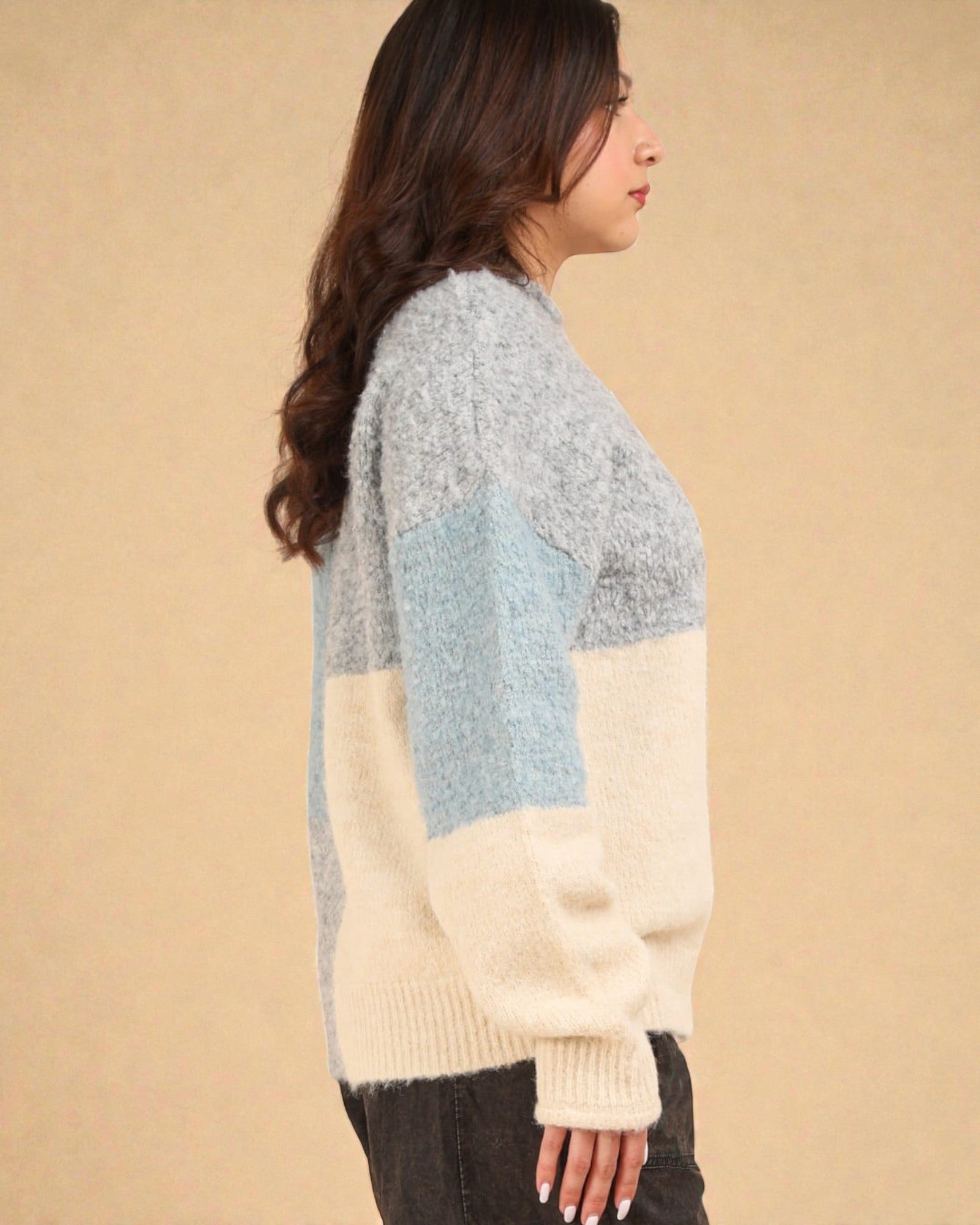 Woman wearing a color-blocked sweater against a beige background