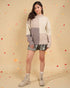 Woman wearing a color-blocked sweater and shorts with a beige background