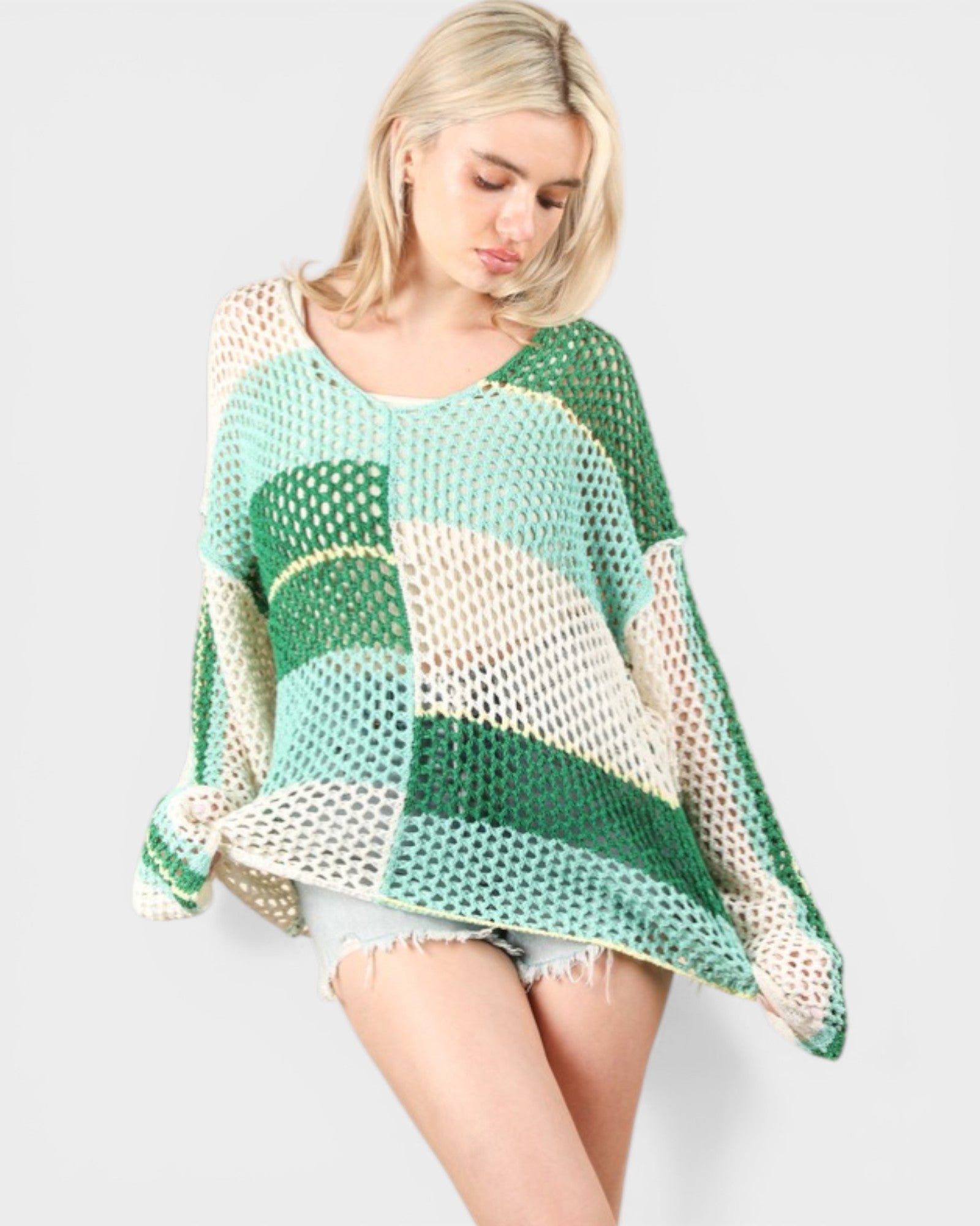 Woman wearing a green and beige patterned poncho on a light gray background
