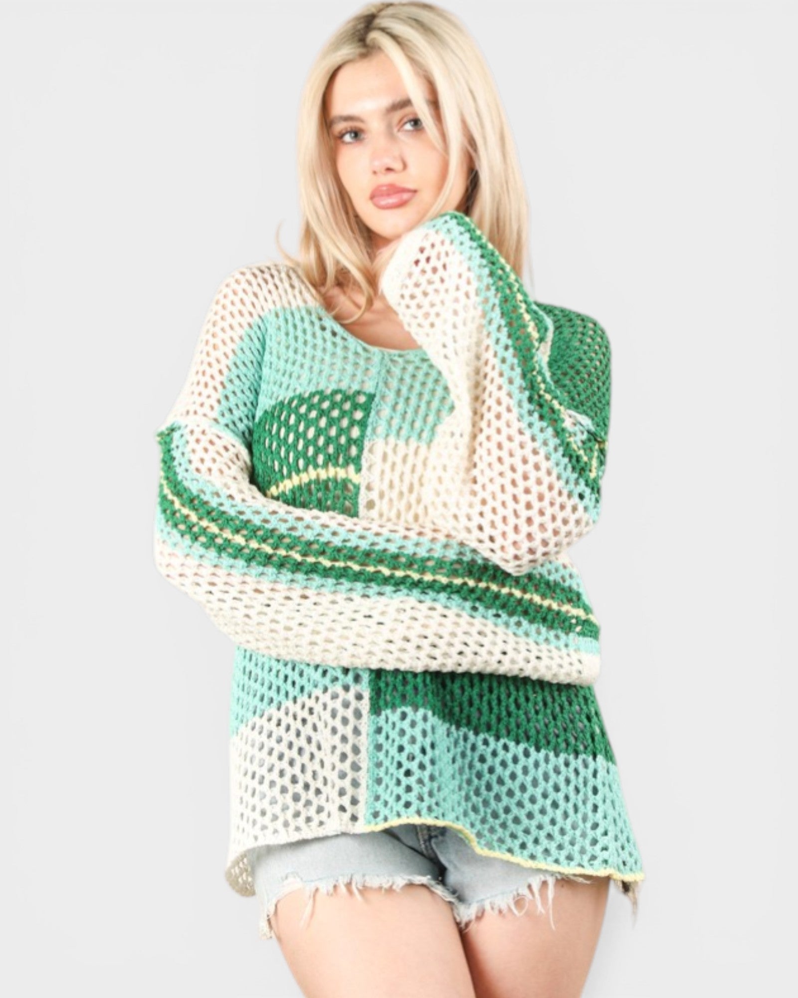 Woman wearing a green and white patterned sweater on a plain background
