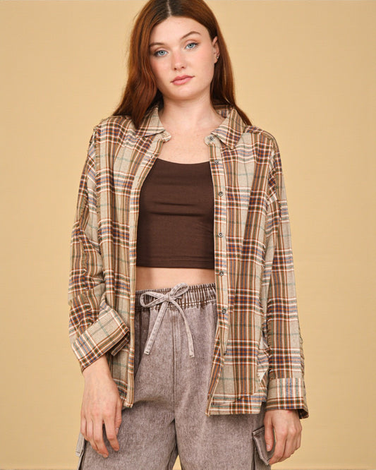Woman wearing a plaid shirt over a brown top and gray pants on a beige background