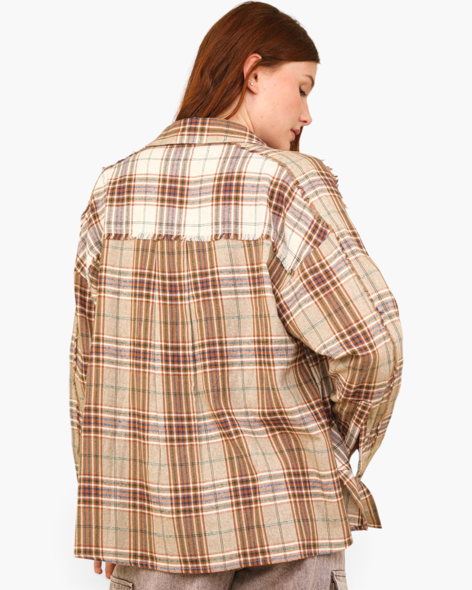 A woman shown from the back wearing an oversized plaid button-up shirt in beige, brown, and cream tones, paired with gray pants, against a plain light gray background.
