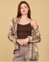 Woman wearing a plaid shirt over a brown top and gray pants on a beige background