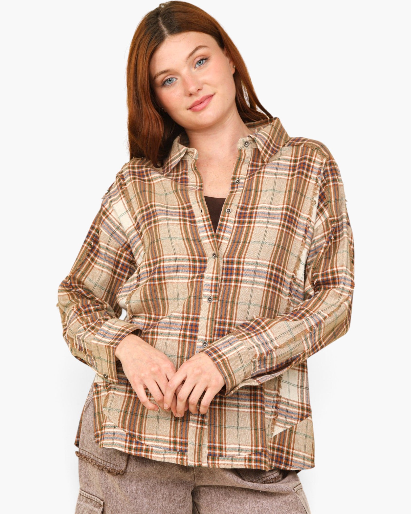 A woman wearing a brown and beige plaid button-up shirt, paired with gray pants, against a plain light gray background.