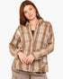 A woman wearing a brown and beige plaid button-up shirt, paired with gray pants, against a plain light gray background.