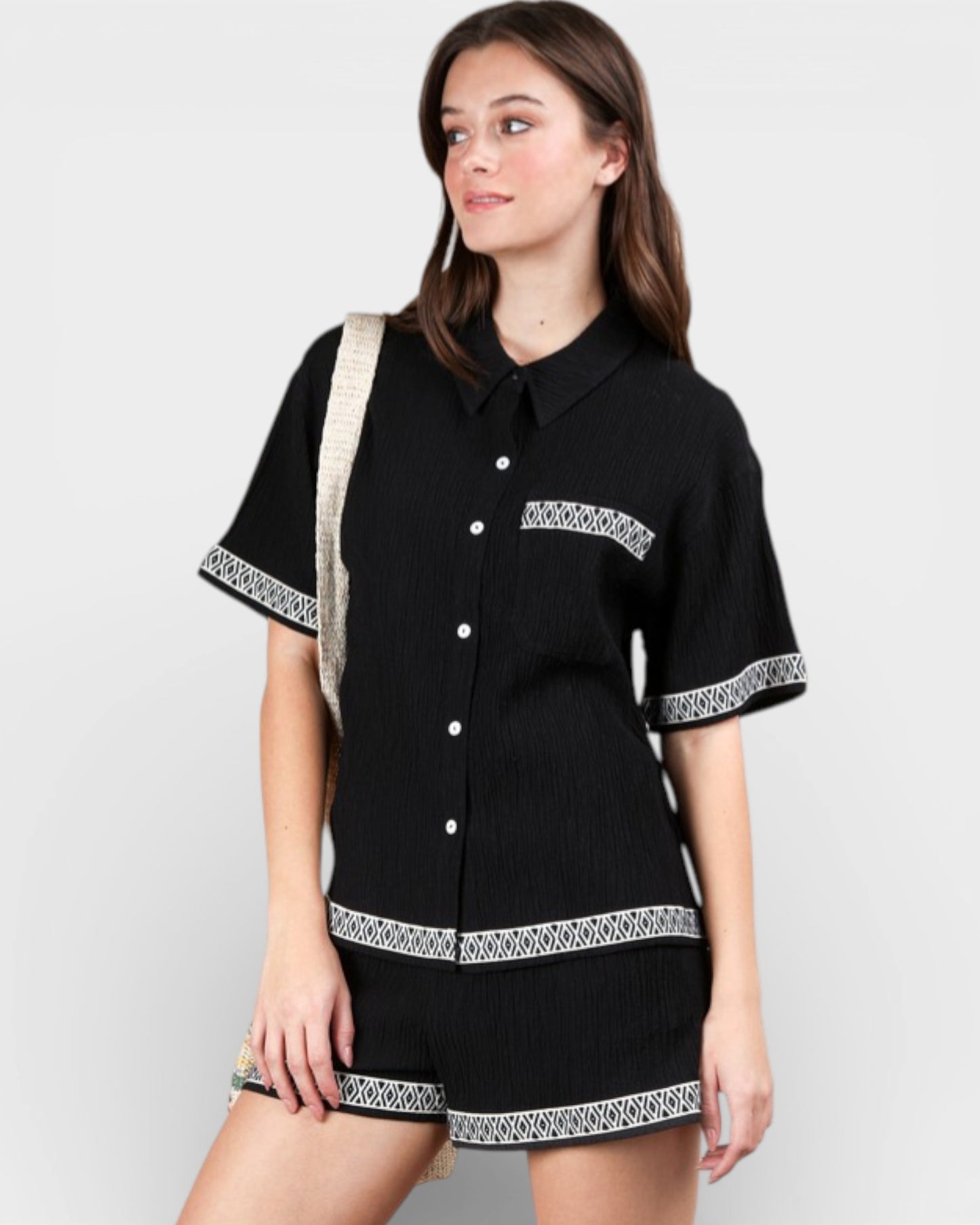 Woman wearing a black dress with white patterns on a plain background